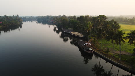 vista idílica de un lago con una casa flotante con un barco con bosque tropical en kerala, alleppey, india