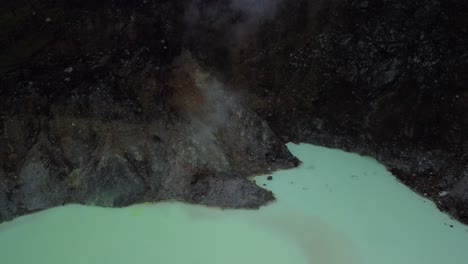 Top-View-Of-The-Famous-Kawah-Putih-White-Crater-with-steam-rising-from-a-vent-In-Bandung,-West-Java,-Indonesia---aerial-drone-shot