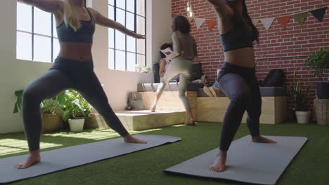 Mujeres-De-Negocios-Jóvenes-Practican-Meditación-De-Yoga-Juntas-En-La-Oficina-Haciendo-Pose-De-Guerrero-Disfrutando-Del-Ejercicio-De-Atención-Plena-Relajándose-Durante-El-Almuerzo