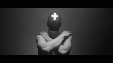 masked man with cross of light glowing on his face moves slowly