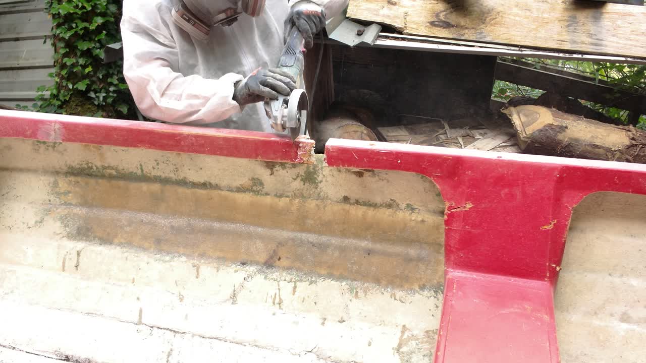 Worker Cutting Old fiberglass Boat Gunwale with Angle Grinder for Repair