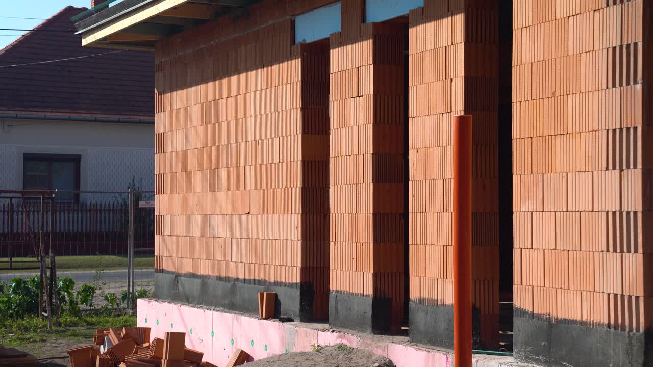 Exterior walls of unfinished brick house with bitumen coated foundation