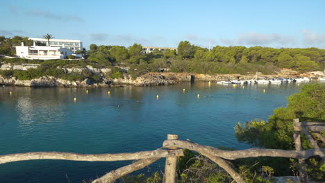 swimmers practicing at dawn in cala santandra cove in menorca, spain