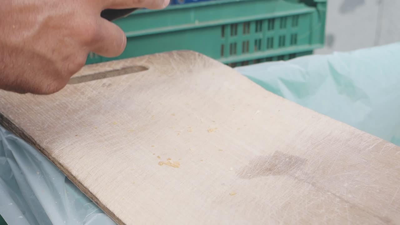 hombre cortando comida en una tabla de cortar de madera