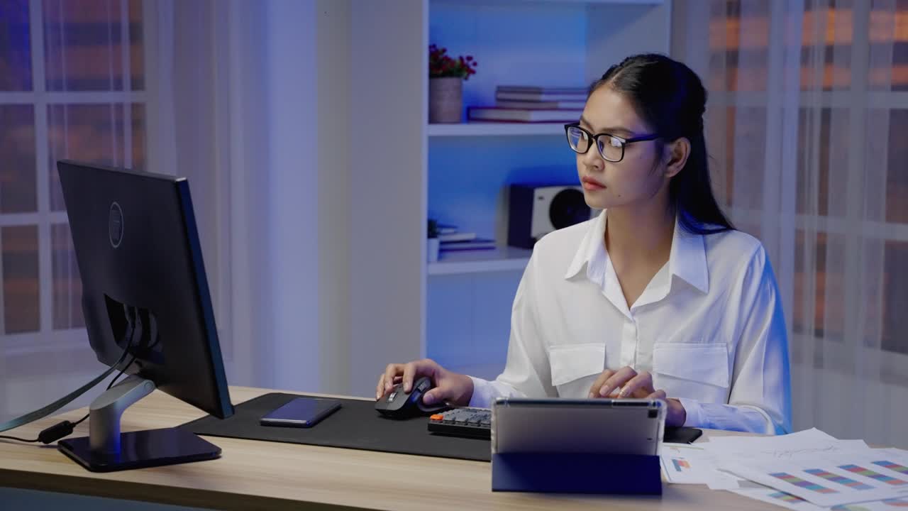 una mujer de negocios asiática o independiente está ocupada en el trabajo, habla por teléfono y escribe hasta horas extras por la noche.