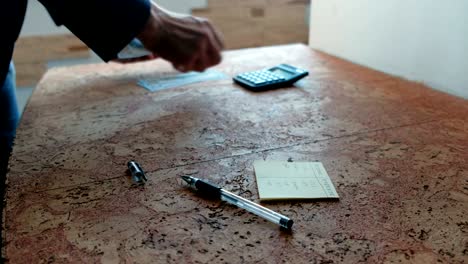 man counts the money laying them on the table with calculator. closeup hands.