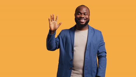 man cheerfully doing salutation hand gesture, studio background