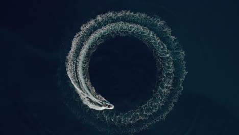 aerial shot of a fast speedboat going around in the circle and making beautiful circle path in the sea