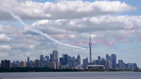 avión de acrobacias rojo volando en la torre cn y el horizonte de la ciudad de toronto, plano general