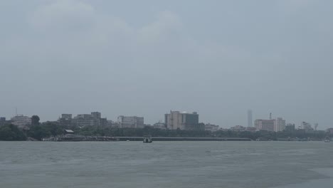 cityscape across a river under a cloudy sky