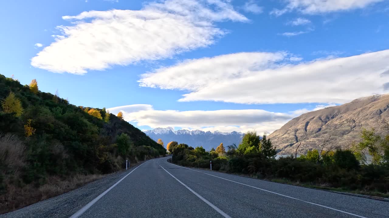 Forward-facing timelapse of car driving along winding mountain road, natural daylight, lush landscape