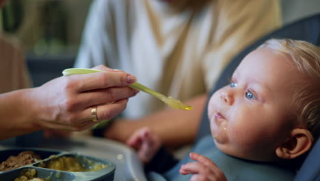 meals time for a cute little infant boy. mother's hand is giving food to her beloved baby. close up.