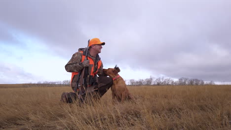 a hunter with rifle gun goes hunting with his pet dog in the wilderness in saskatchewan, canada - full shot