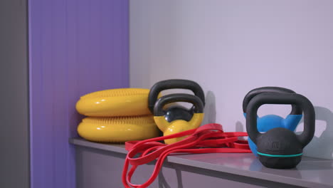 kettlebells, resistance bands, balance discs, and other gym equipment neatly arranged on shelf in fitness studio, creating an organized space for strength training, and core exercises