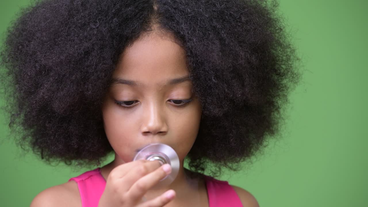 joven chica africana con cabello afro jugando con el girador inquietante