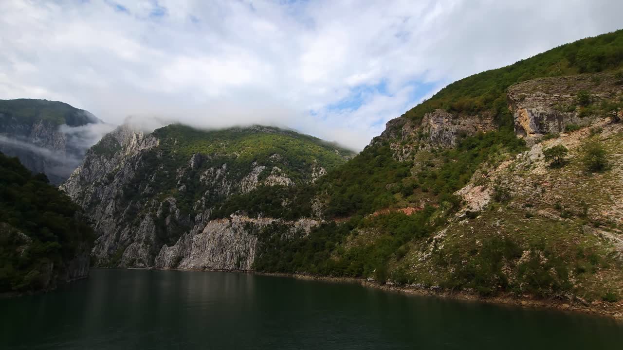 el sereno lago de koman: aguas tranquilas y verdes en contraste con las majestuosas laderas rocosas de los alpes albaneses