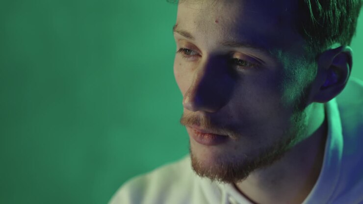 Ritratto di un giovane uomo che usa un computer su uno sfondo verde e colorato. Primo piano.