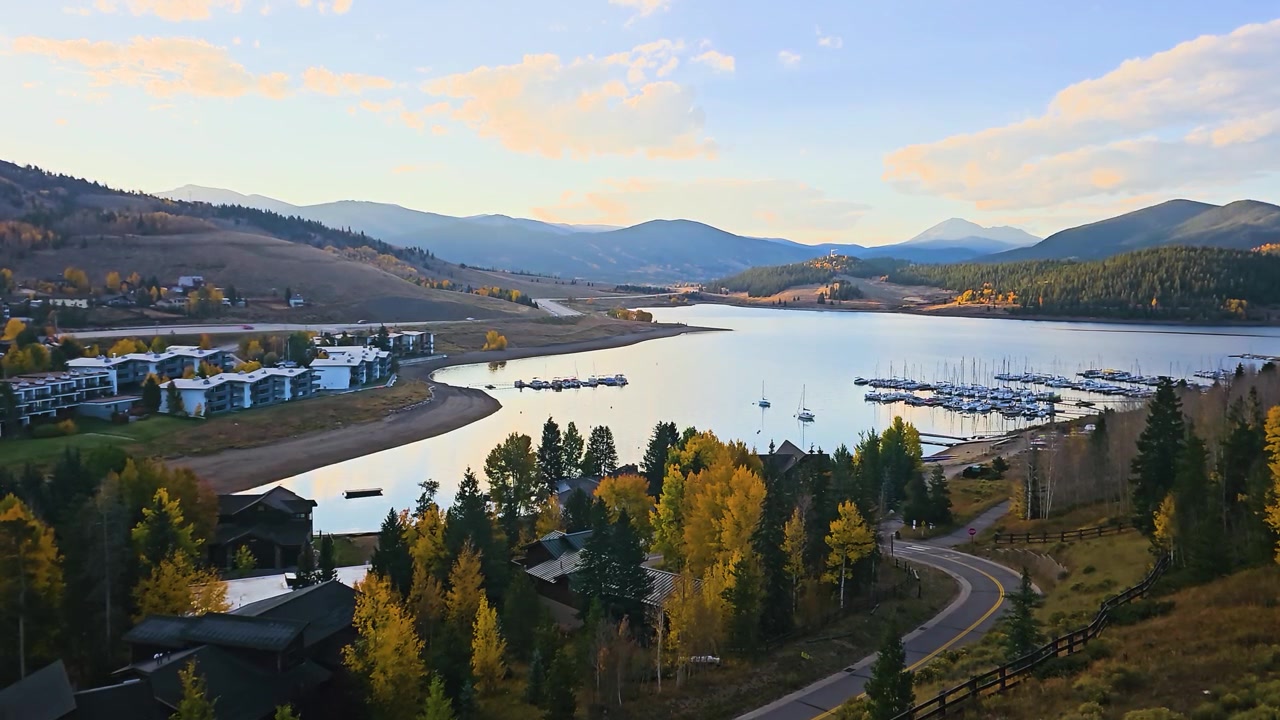 Paesaggio all'ora d'oro a Dillon, Colorado, con marina sul lago, strada tortuosa, pioppi tremuli gialli, case di montagna e acqua calma del bacino che riflette la luce soffusa della sera