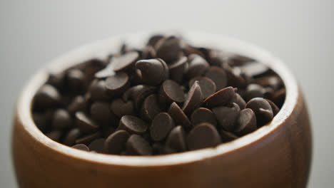 Video-of-close-up-of-wooden-bowl-of-chocolate-chip-over-grey-background