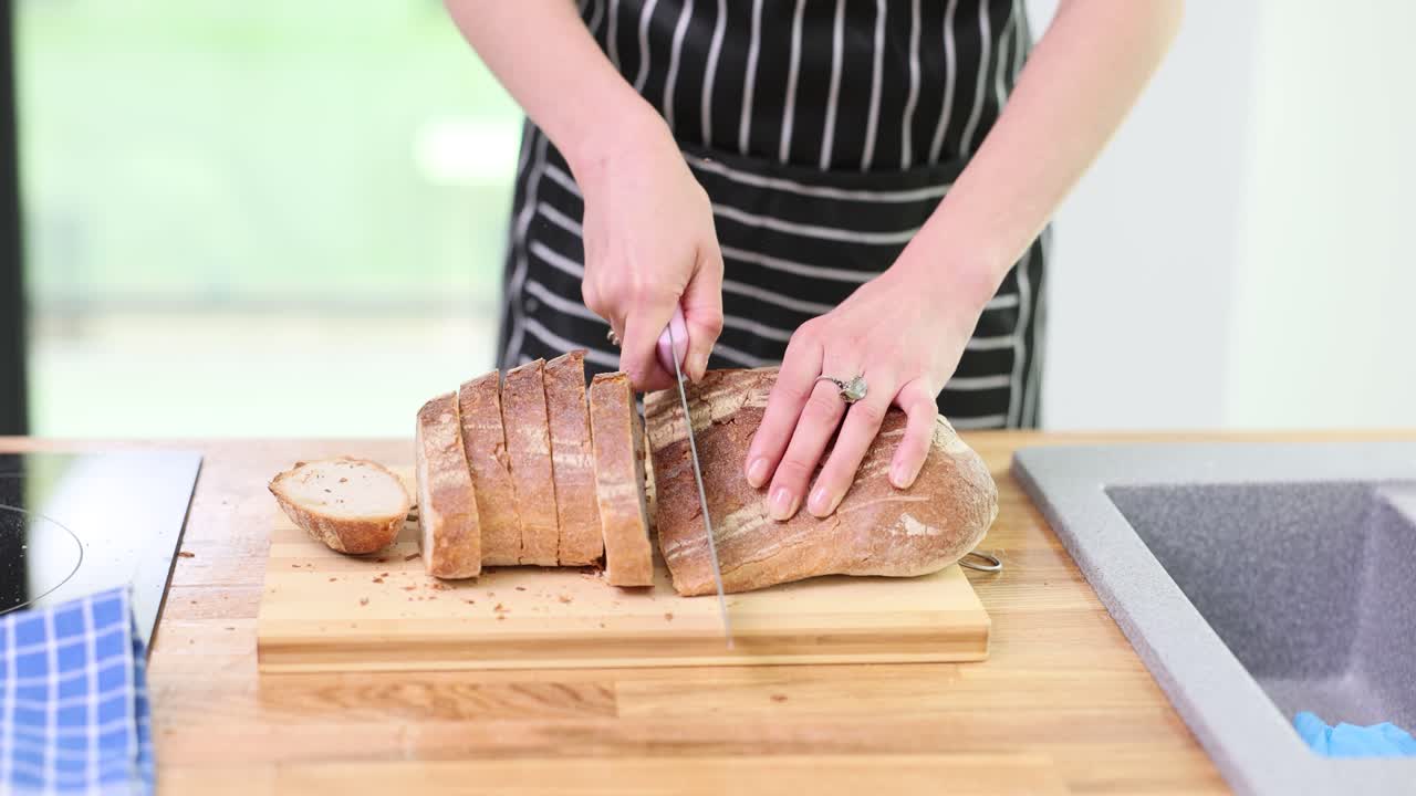 Person slicing a loaf of fresh bread in a kitchen
