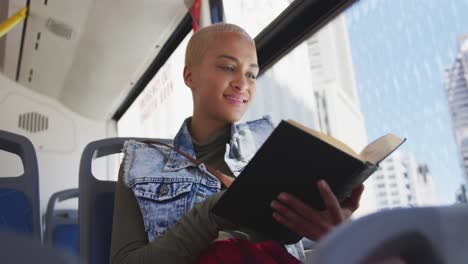 mujer de raza mixta tomando el autobús y leyendo un libro