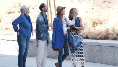 happy mature friends walking on city street and looking up in wonder