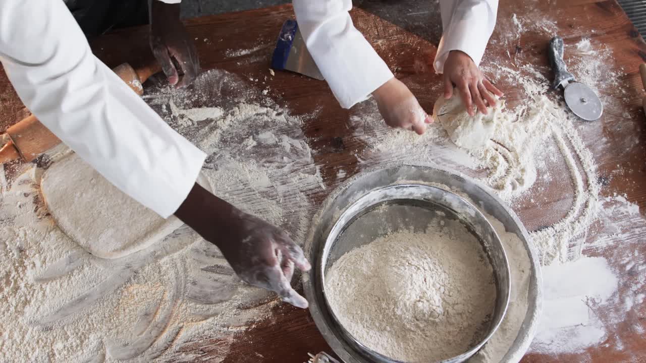 Diverse bakers working in bakery kitchen, kneading dough on counter in slow motion