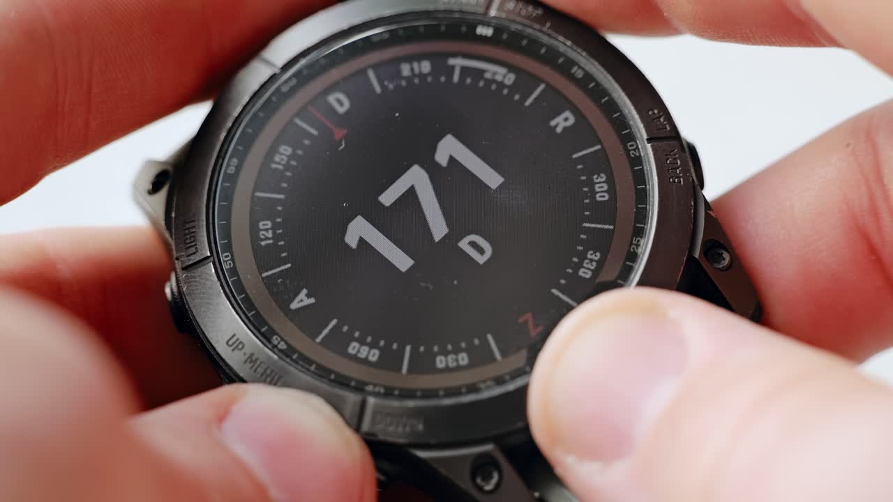 Close-up of compass interface on smartwatch as man holds and adjusts it