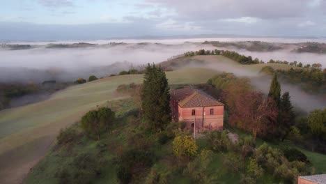 Italian-style-farm-house-on-remote-hill-in-Tuscany-overlooking-valley,-aerial