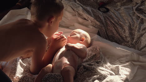 boy with baby at home he loves little sister and kissing her on the cheek