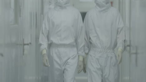 scientists or researchers equipped with protective suits, face masks, shoe covers and safety goggles, walking in laboratory sterile corridor, exuding a sense of safety and caution.