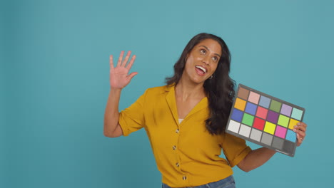 mature female model posing against background on studio shoot holding colour checker card for video