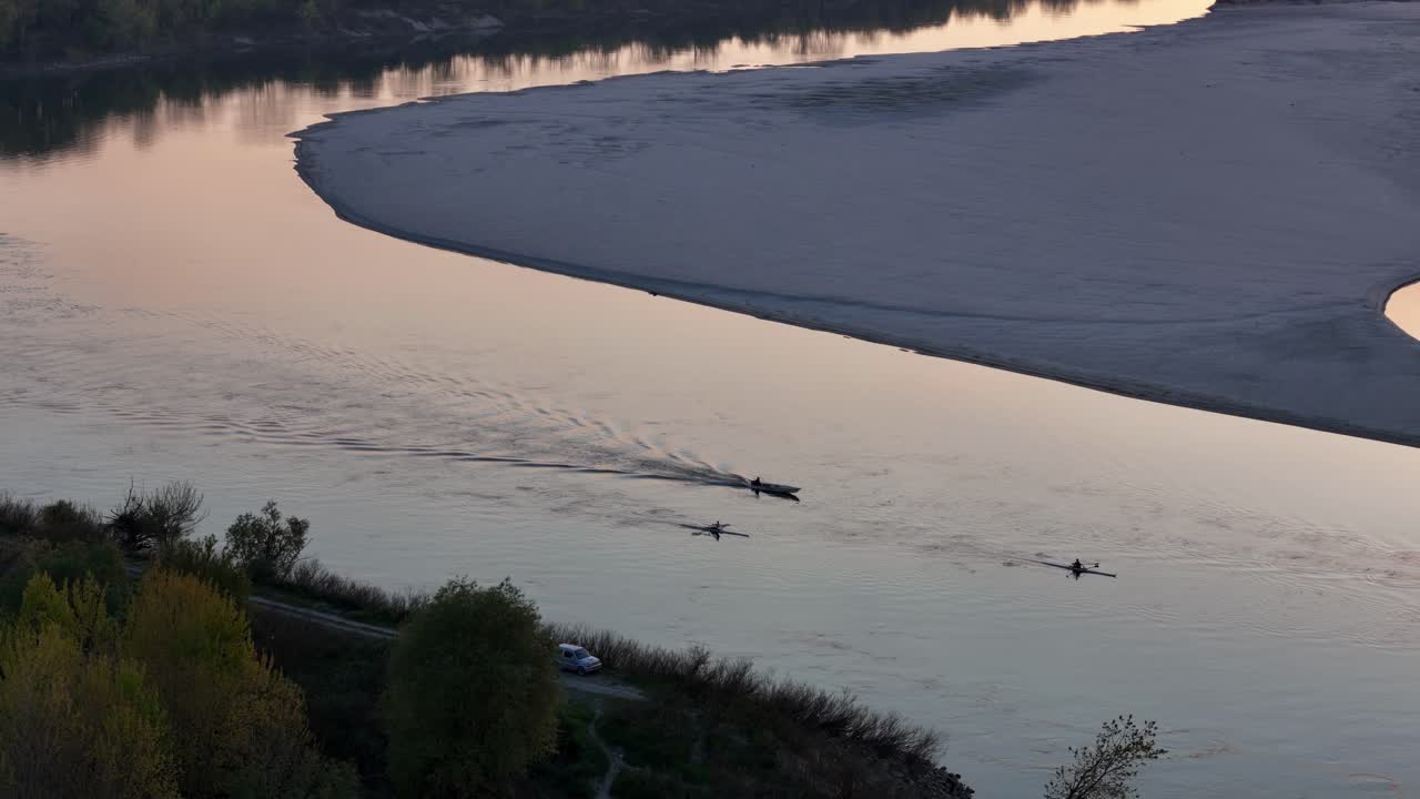 At sunset, three boats carve gentle wakes across the River Po near Cremona, their motion framed by sandy banks, autumn light, and quiet riverside textures in northern Italy, slow motion shot