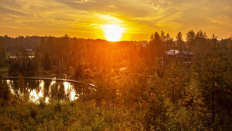 beautiful time lapse shot of golden morning sunrise at natural lake surrounded by forestry in nature - bright sunbeam shining at cloudy sky - 5k wildlife shot