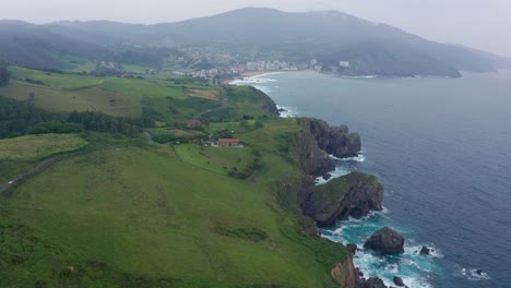 sea near rocks and houses under blue cloudy sky
