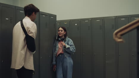 Couple-joyful-students-talking-standing-at-lockers-lively-school-corridor.