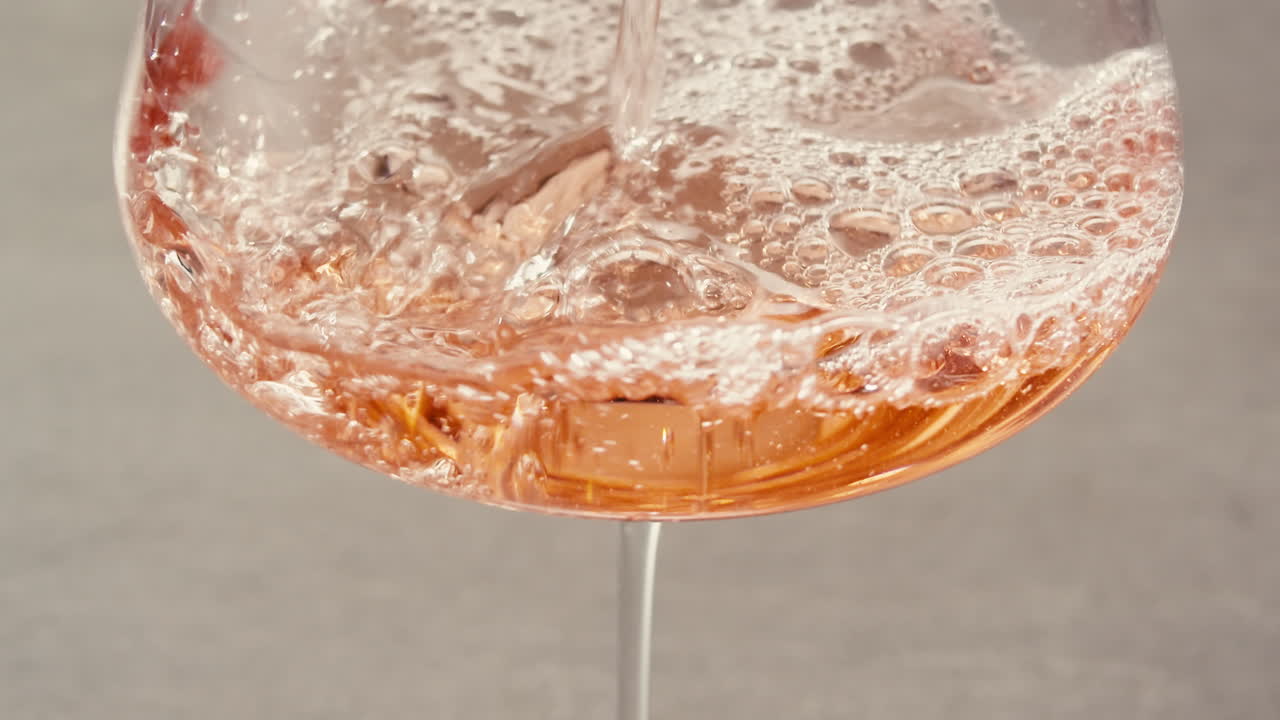 Orange or white wine bottle and glass against a sunset in a peaceful vineyard, pouring of ecological natural wine.