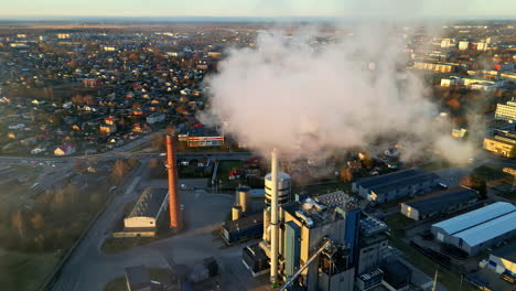 smoking factory chimneys, polluting in a sunlit urban community - aerial view