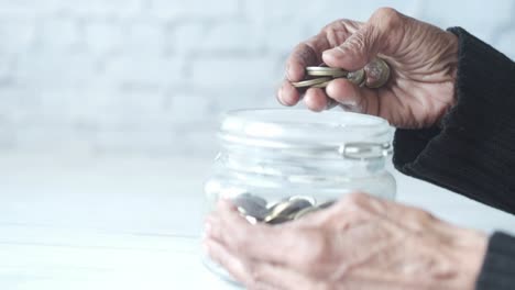 persona de edad avanzada guardando monedas en un frasco