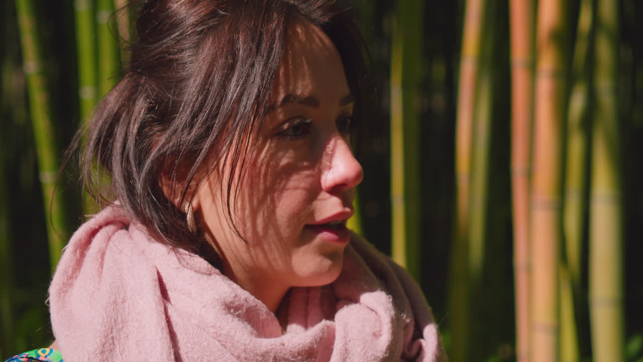 una chica morena mira hacia arriba y luego continúa, lleva una bufanda rosa