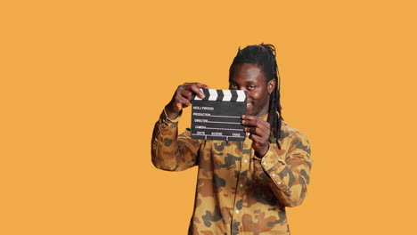 male model posing with clapperboard in front of camera