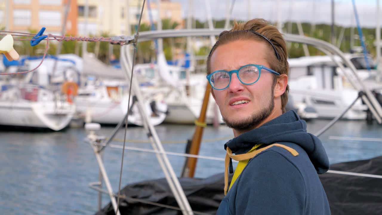 Slow motion shot of a male captain looking around the marina at the other boats