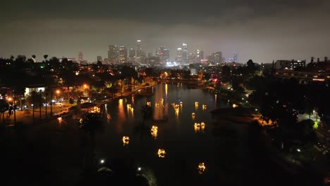 glowing swan pedal boats on echo lake with the los angeles city skyline - aerial flyover