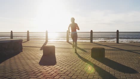 African-american-woman-running-on-promenade-by-the-sea-at-sundown