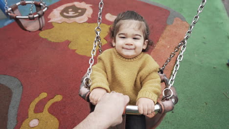 gimbal slow motion shot of baby playing with his father on swing with social distance