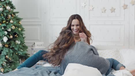 smiling family tickling each other on bed in sleeping room together.