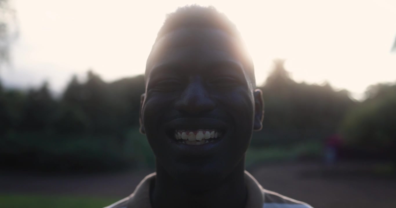 Portrét usměvavého mladého Afričana prosvětleného sluncem