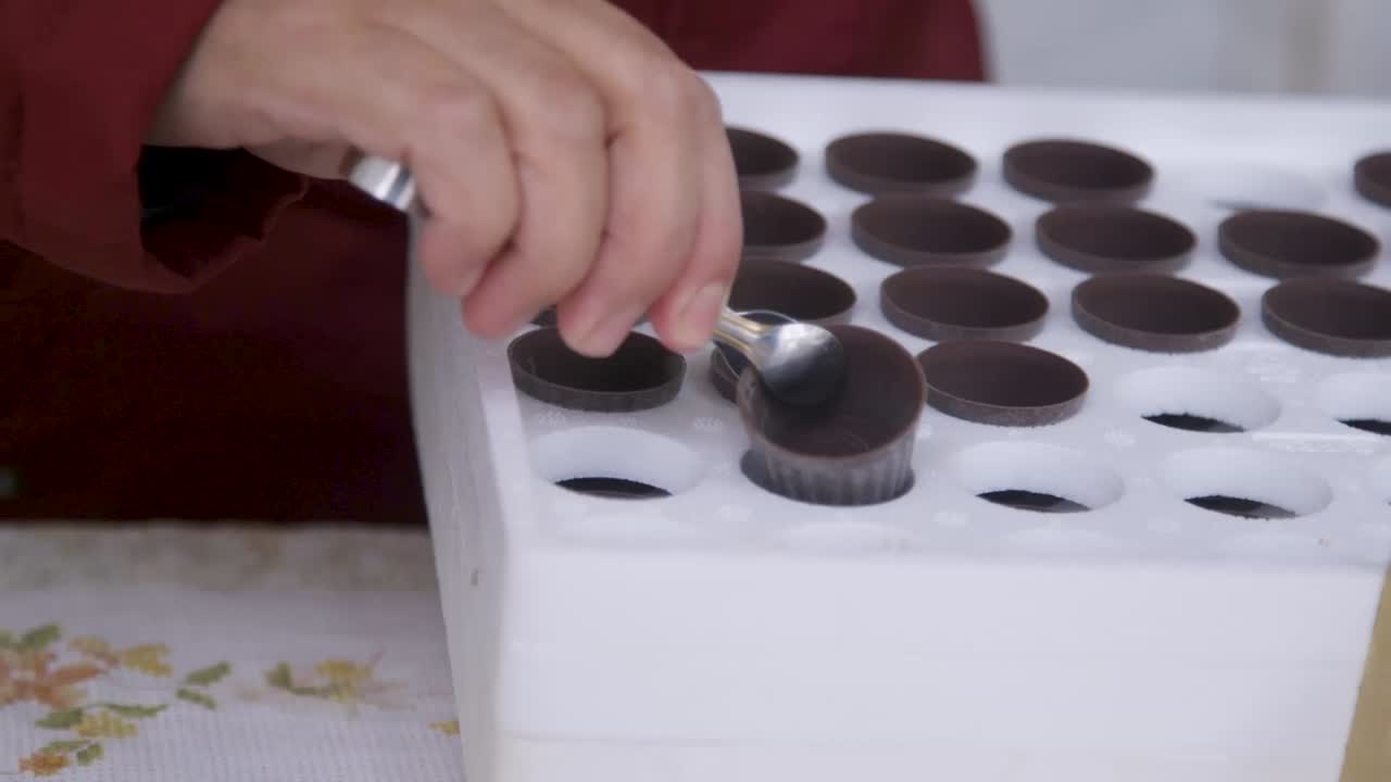 Woman picking chocolate cups to serve ginjinha, detail shot. Mirandela, Vale de Salgueiro, Portugal