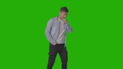 foto de estudio de un joven vestido casualmente estornudando contra una pantalla verde