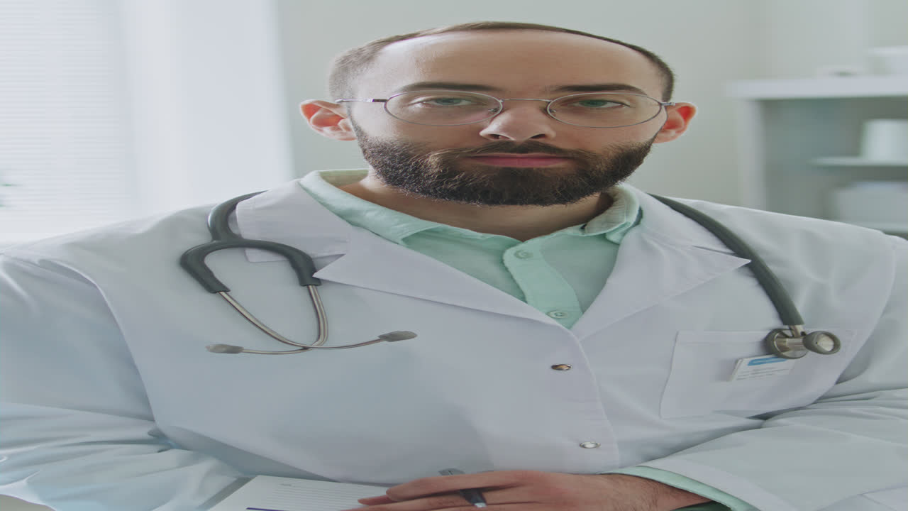 Ritratto verticale di un medico uomo che guarda la telecamera durante la giornata lavorativa in clinica